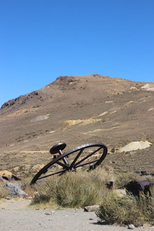 Large machine wheel on a mound, hill in background.