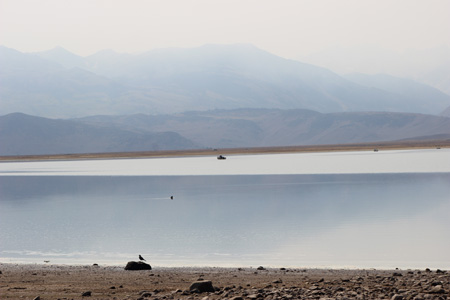 Expanse of lake with smoke obscuring the mountains.