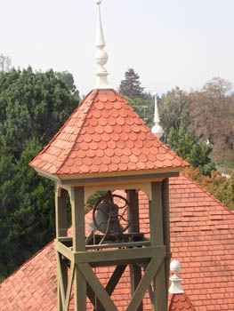 Bell tower, peaked roof, red circular shingles. 
