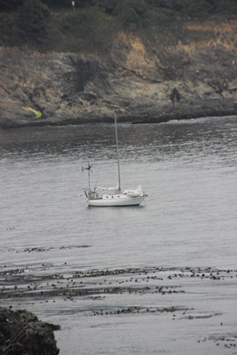 Calm see with a white boat at anchor, cliffs in background